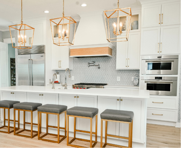 Bright white kitchen with island seating, pendant lights, and cabinet display